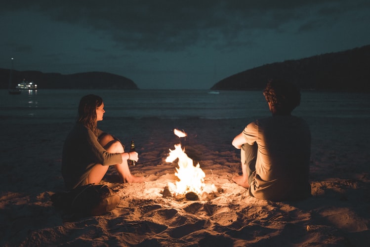 Couple enjoying bonfire by the beach 